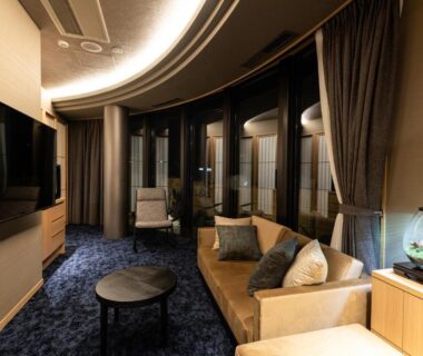 Curved-window lounge with sofa, armchairs and TV at Arima Onsen ShikinoIrodori Hatago, Hyōgo, Japan