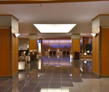 Spacious tiled lobby with wooden columns, seating areas and recessed skylight at Arima Onsen Taketoritei Maruyama in Hyōgo