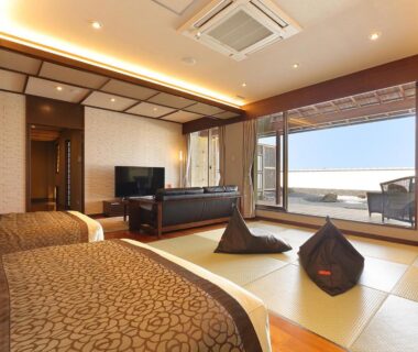 Spacious tatami room with twin beds, low seating and balcony at Arima Onsen Taketoritei Maruyama