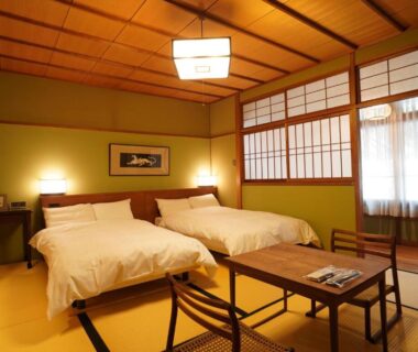 Tatami room with twin beds, shoji screens, low table and warm ambient lighting at Arima Onsen Tocen Goshobo Hyōgo