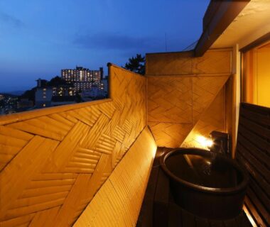 Wooden balcony bath at dusk with bamboo wall and city lights visible, Arima Royal Hotel, Hyōgo