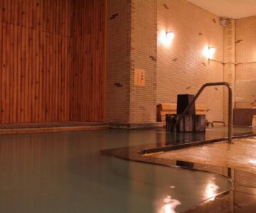 Tiled indoor onsen bath with wooden wall panels and entrance steps at Arimakan in Yamagata Tōhoku