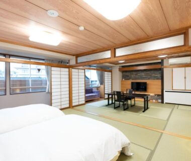 Japanese tatami room with twin beds, low table, shoji screens and wooden ceiling at Arimakan, Yamagata