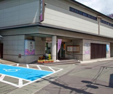 Street-level entrance with visible parking and accessible bays at Arimakan ryokan in Tōhoku, Yamagata