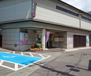 Street-level entrance with visible parking and accessible bays at Arimakan ryokan in Tōhoku, Yamagata