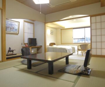 Tatami room with low table, chairs, beds and shoji screens at Arimakan in Yamagata, Tōhoku, Japan