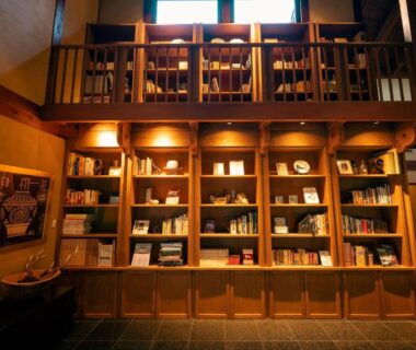 Warm wooden library with mezzanine, floor-to-ceiling bookshelves and reading lamps at Arimasansoh Goshobessho, Hyōgo