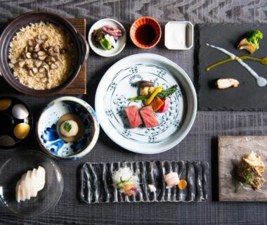 Assorted Japanese small dishes and sashimi with rice pot and condiments on elegant tabletop arrangement