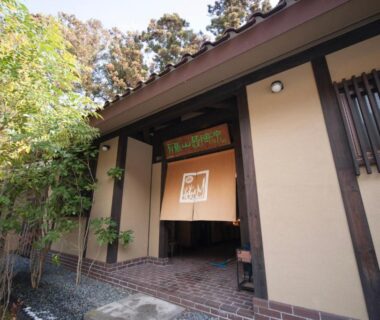 Ryokan entrance with noren curtain, wooden beams and bamboo plantings at Arimasansoh Goshobessho in Hyōgo