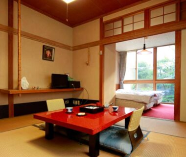 Tatami room with low lacquer table, floor chairs and futon by window overlooking garden at Aritaya Ryokan, Nagano
