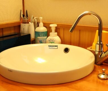 Round ceramic sink with chrome faucet and toiletries on wooden counter in Aritaya Ryokan bathroom Nagano