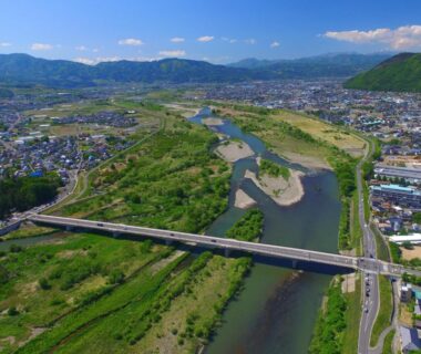 Aerial view of river and bridge near Aritaya Ryokan in Nagano Chūbu with town and mountains visible