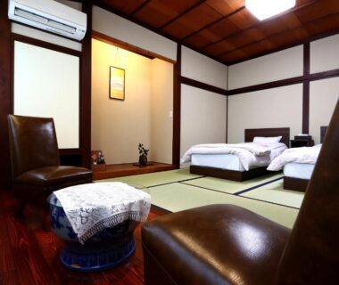Interior showing tatami flooring, twin beds, leather chairs, wooden ceiling in Aritaya Ryokan, Nagano