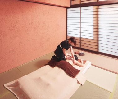 Therapist giving massage on futon in tatami room with shoji screens at Arujisu, Shizuoka