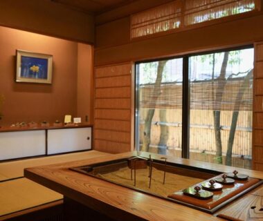 Traditional tatami room with recessed wooden soaking area, low table, shoji screens and bamboo garden view in Ishikawa