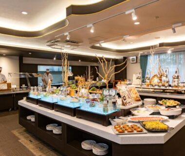 Buffet counters with assorted dishes and chefs in a bright ryokan dining hall at Asagiriso Hyōgo
