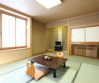 Tatami room with low table, floor chairs, shoji window and tokonoma at Asahikan Nagano