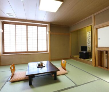 Tatami room with low table, cushions and shoji screens at Asahikan in Nagano, Chubu, Japan