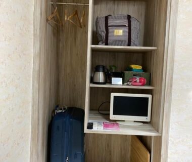 Open wooden wardrobe with suitcase, hangers, kettle and small TV at Asakusa Ryokan Toukaisou Tokyo