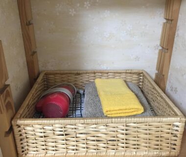 Woven basket with yellow towel and toiletry on wooden shelf at Asakusa Ryokan Toukaisou Tokyo