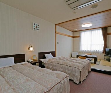 Spacious guest room with two beds, raised tatami seating area and low table at Ashinomaki Prince Hotel, Fukushima