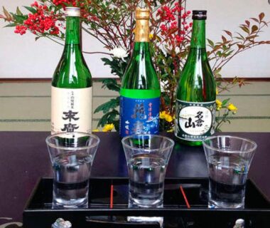 Sake bottles and three glasses on a tray in a tatami room at Ashinomaki Prince Hotel, Fukushima