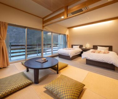Bright tatami room with twin beds, low table and riverside view at Ashionoyado Kajika in Tochigi, Kantō Japan