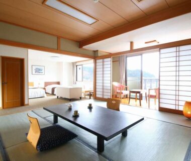 Tatami room with low table, shoji screens, twin beds and balcony with mountain view at Ashiwada Hotel Yamanashi