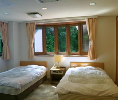 Bright twin room with bedside lamp and green foliage visible through windows at Asia Hotel FUJISAN, Yamanashi