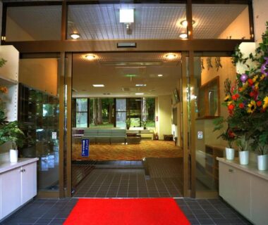 Glass entrance with red carpet and potted plants at Asia Hotel FUJISAN lobby, Yamanashi, Chūbu
