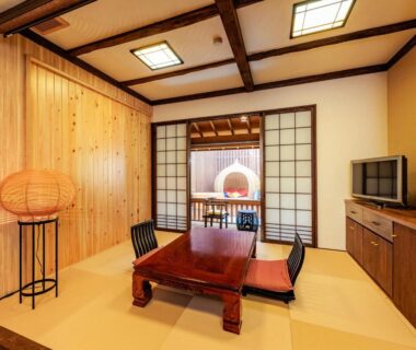 Traditional tatami room with low wooden table, floor chairs, shoji screens and wooden paneling at AsoTsuruya in Kumamoto
