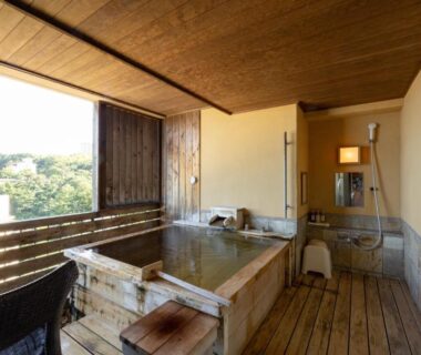 Wooden soaking tub on room balcony with outdoor shower and forested hill views at Atagawa Prince Hotel, Shizuoka