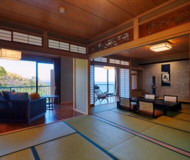 Spacious tatami room with low table, seating area, shoji screens and sea view through large windows