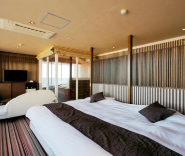Twin beds, modern seating and balcony view at Atagawa Yamatokan in Shizuoka