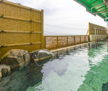 Tiled onsen bath with bamboo fence and rocks at Atagawa Yamatokan Shizuoka