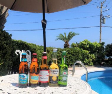 Assorted bottled drinks on white table beside outdoor pool and umbrella at Atagawa Yamatokan in Shizuoka