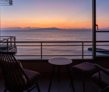 Two chairs and table on balcony overlooking calm sea sunset at Atagawakan, Shizuoka, Chūbu, Japan