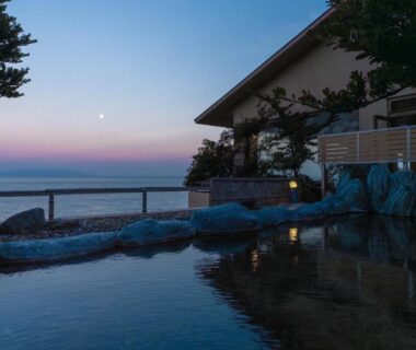 Seaside onsen at Atagawakan with stone bath and coastal horizon in Shizuoka