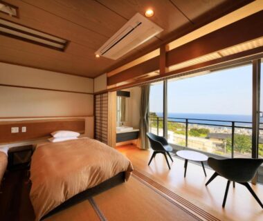 Japanese-style tatami room with two beds and balcony overlooking coastline at Atami Fuga, Shizuoka