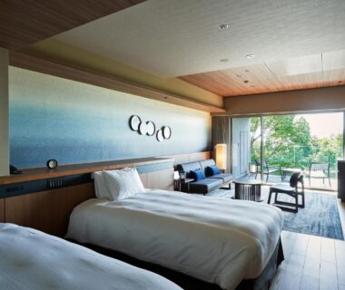 Twin beds and seating area at Atami Izusan Karaku with balcony overlooking greenery in Shizuoka Chūbu
