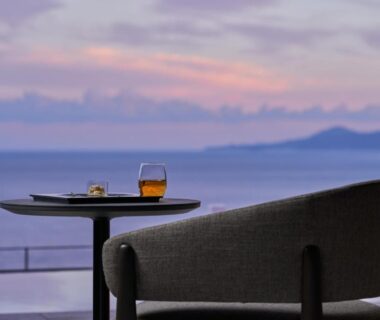 Balcony table and chair with drink overlooking coastal waters at Atami Izusan Karaku, Shizuoka