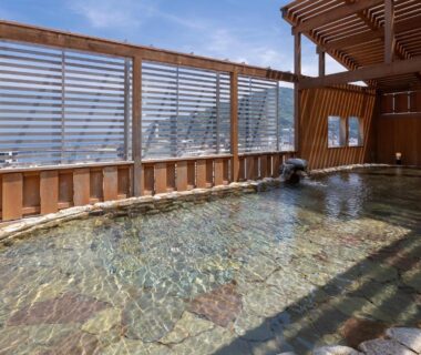 Outdoor stone onsen bath at Atami New Fujiya Hotel with wooden lattice screen in Shizuoka, Chubu Japan