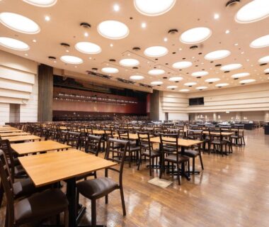 Spacious banquet hall with wooden tables and stage at Atami New Fujiya Hotel, Shizuoka