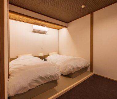 Raised tatami alcove with twin beds and bedside lamp at Atami Onsen Yamaki Ryokan in Shizuoka, Chūbu