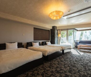Three single beds with seating by window at Atami Season Hotel Shizuoka