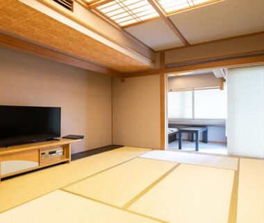 Spacious tatami room with low table, shoji screens and TV at Atami Season Hotel in Shizuoka