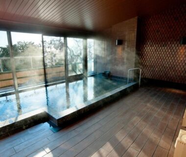 Indoor onsen bath with glass windows overlooking coastal view at Atami Sekaie Shizuoka