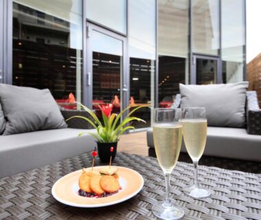 Outdoor terrace sofa with two glasses of sparkling wine, plate of cookies and potted plant at Atami Tensui, Shizuoka