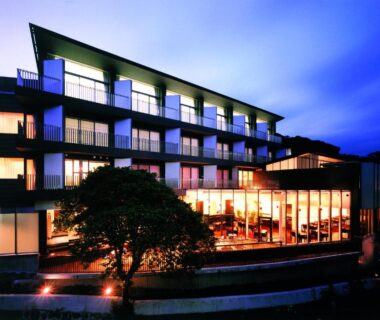 Multi-story ryokan with illuminated balconies and large glass windows at dusk in Atami Shizuoka