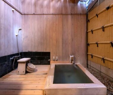 Rectangular stone onsen tub in wooden indoor bathing area with stool and bamboo wall, AtamiOnsen Nagahamaen Shizuoka